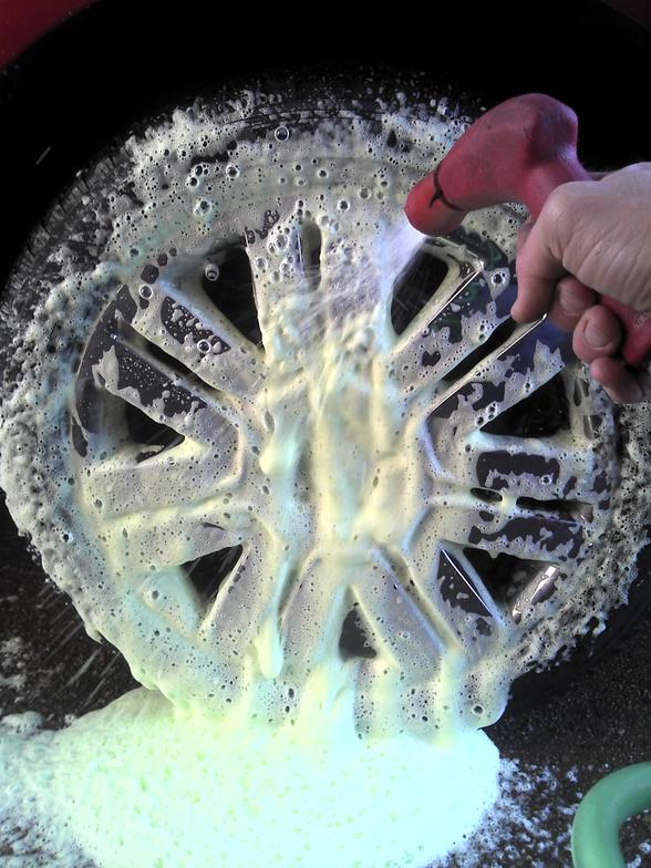 Close-up of foamy wheel being cleaned with red gun tire cleaner